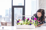 Woman smiling, looking at petunias growing in the Click & Grow Smart Garden 9.